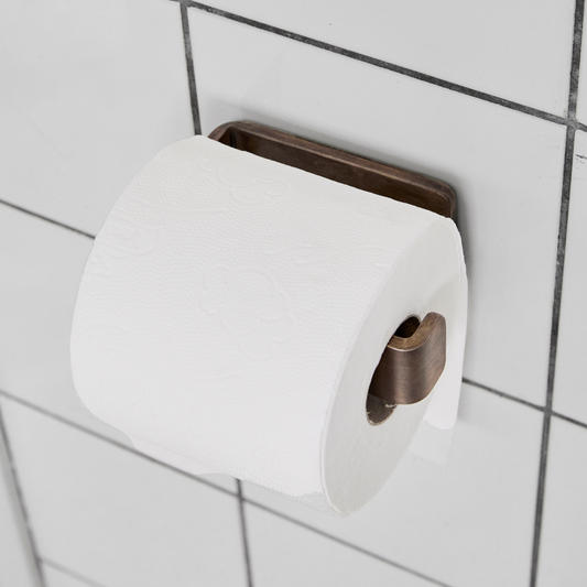 Smuk og stilfuld toiletrulleholder i ubehandlet, bruneret messing.